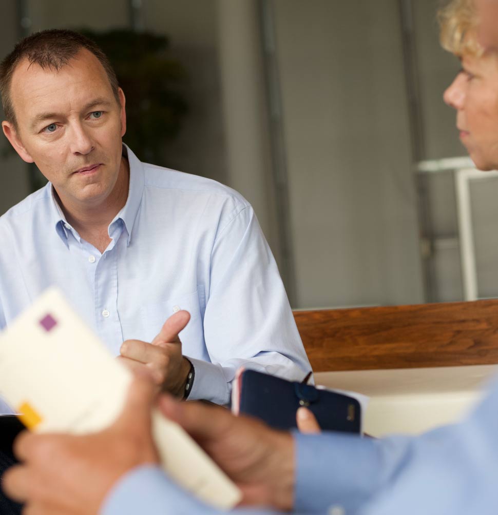 Mann im Gespräch mit zwei Personen – steht für persönliche Begegnung bei der Beratung
