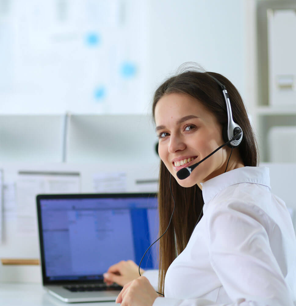 Junge Frau mit Headset lächelt am Laptop – vermittelt Gesprächsbereitschaft in der Seelsorge