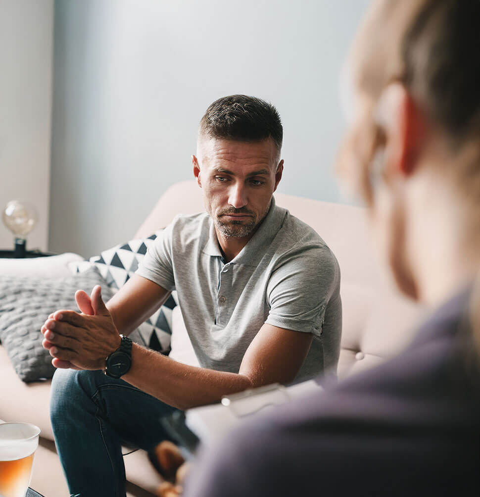 Mann sitzt nachdenklich im Gespräch – symbolisiert Offenheit und Vertrauen in der Beratung.