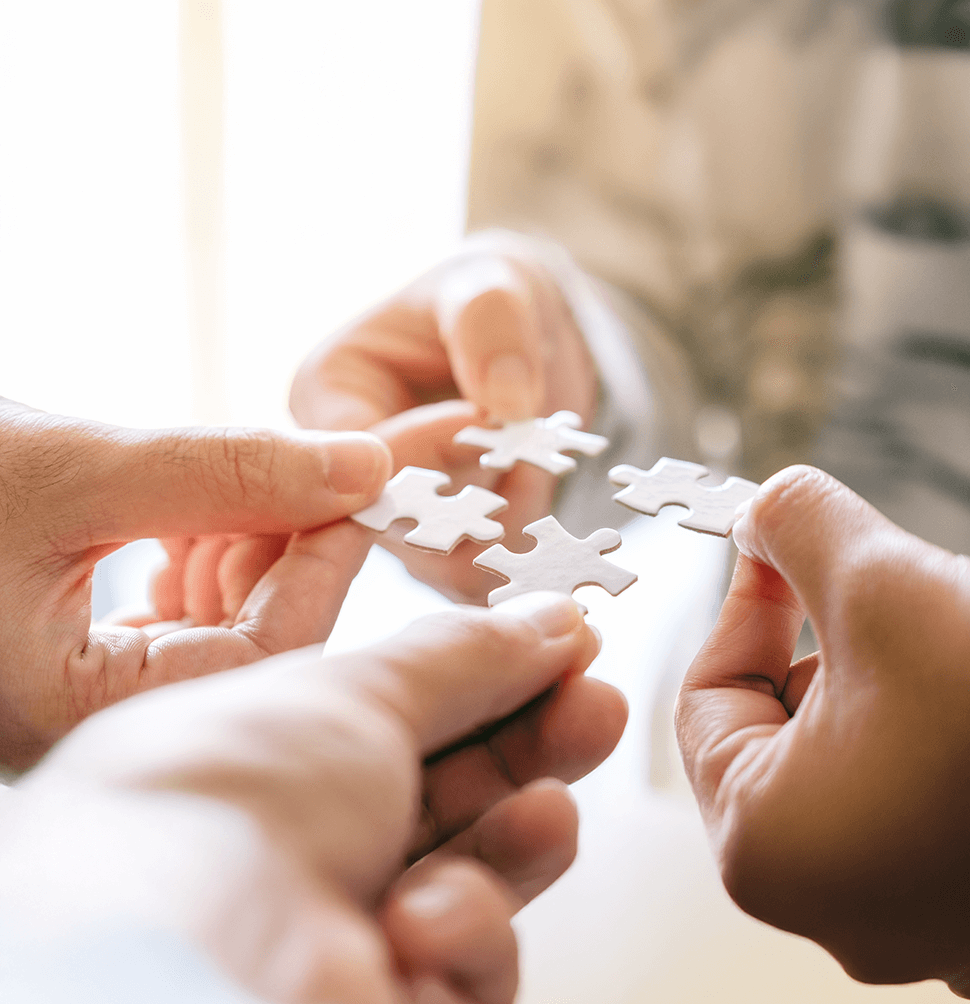 Mehrere Hände halten Puzzleteile und stehen für Verbindung und gemeinsames Helfen.