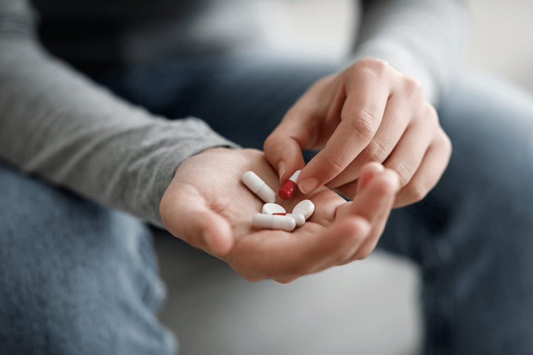 Hand mit Tabletten – steht für Verzweiflung und die Bedeutung rechtzeitiger Hilfe.