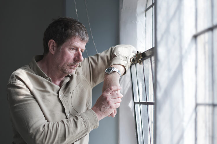 Ein nachdenklicher Mann blickt traurig aus dem Fenster.